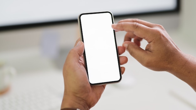 Close up view of male freelancer typing  phone while sitting in workspace