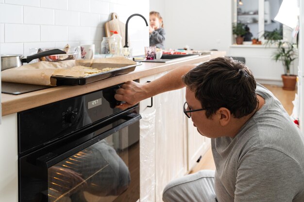 Photo close up view of the male person in apron standing in front of the open oven