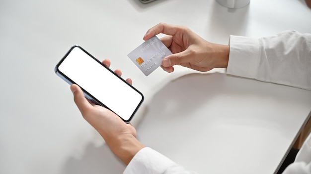 스마트 폰과 신용 카드 온라인 쇼핑 전자 상거래 인터넷 뱅킹 개념을 들고 있는 사람의 손을 가까이서 봅니다.