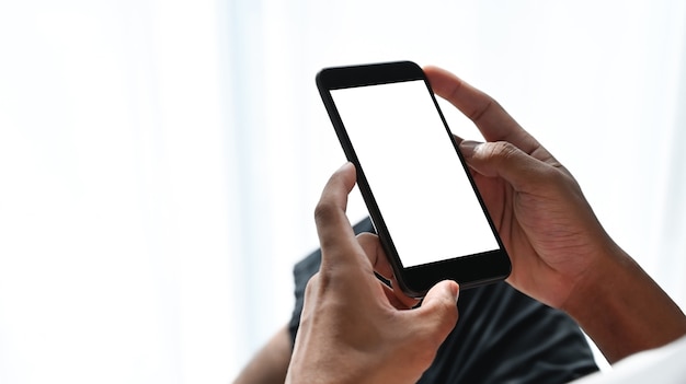 Close up view of man hands holding smart phone with white screen. Blank screen for your text message or information content.