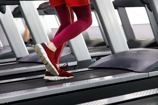 Крупный план человека, бегущего в тренажерном зале на беговой дорожке для занятий фитнесом и здорового образа жизни