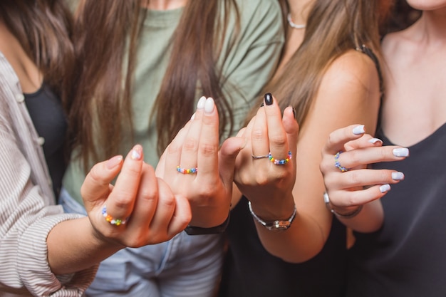 Close-up view of a man's hand showing a ring with an LGBT rainbow wristband.