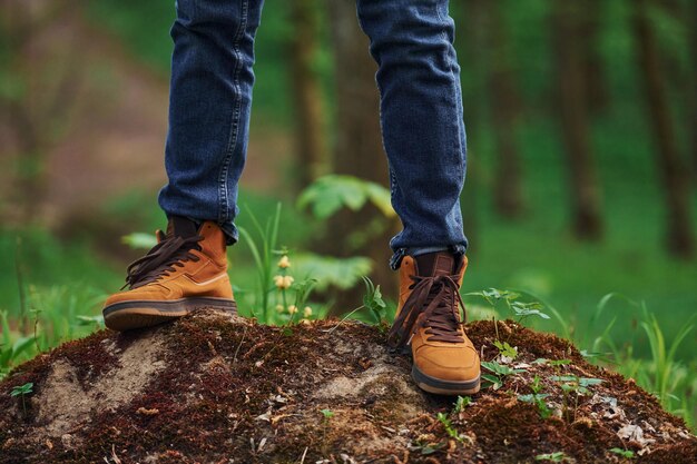 Vista ravvicinata delle gambe dell'uomo sulla roccia nella foresta il viaggiatore fa una passeggiata