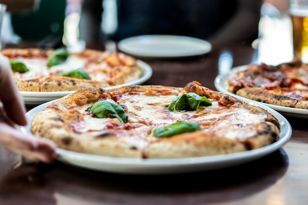 Close up view of a Margherita Neapolitan style pizza with buffalo mozzarella tomato sauce and basil Waiter hand serving pizza at pizza restaurant