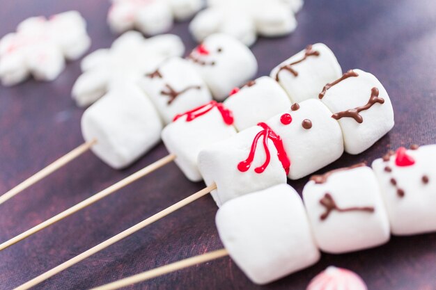 Close up view. Marshmallow snowmen and reindeer on sticks for hot chocate drink.