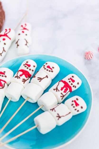 Close up view. Marshmallow snowmen on sticks for hot chocate drink.