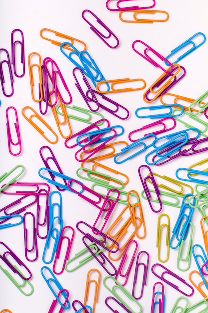 Close up view of a mess of several colorful office paper clips isolated on a white background.