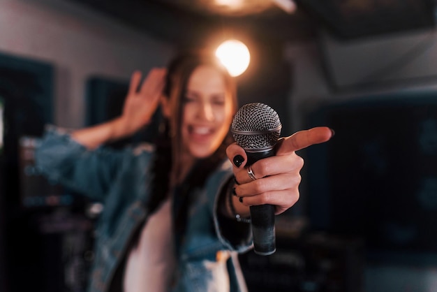 Close up view of microphone Young beautiful female performer rehearsing in a recording studio