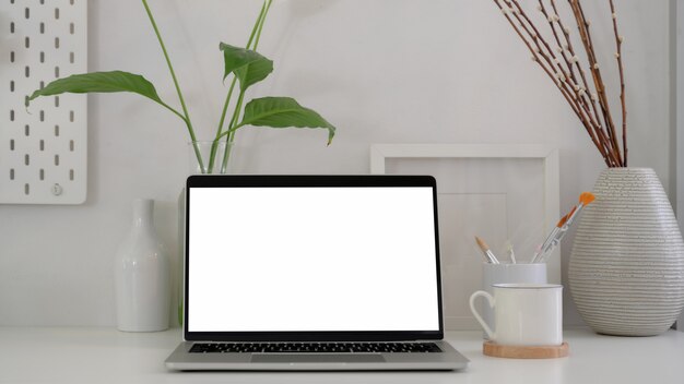 Close up view of modern artist workplace with blank screen laptop , painting brush and decorations