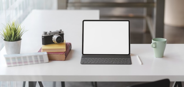 Photo close-up view of modern office room with blank screen tablet, camera and office supplies