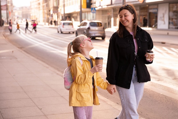 通りを歩いている母と娘のクローズアップビューとお互いを見てください