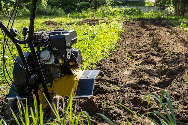 A close up view on motor cultivator during plow process spring season garden works concept