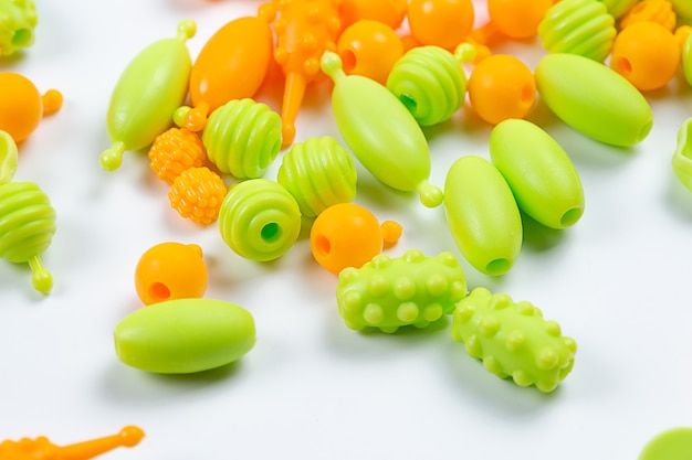 Close-up view of Multicolored plastic beads for a girl's bracelet from a set for needlework on a white background