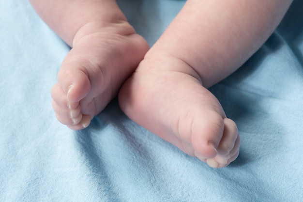 Close up view of newborn baby legs on a bed.