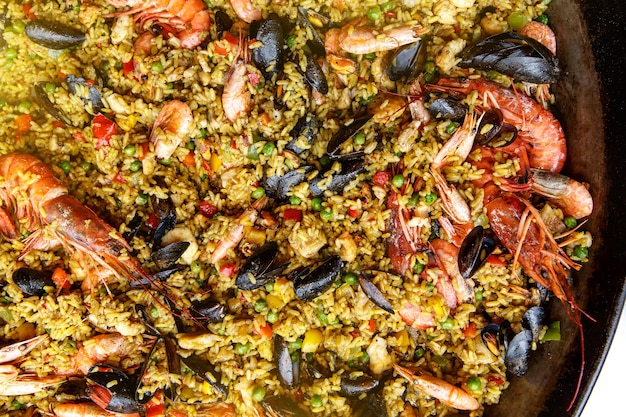 Фото Крупным планом вид испанской паэльи из морепродуктов: мидии, королевские креветки, лангустин, пикша.