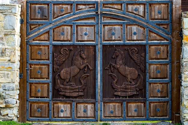 Close up view of an old, rustic, massive, wooden, door with decorative carvings.