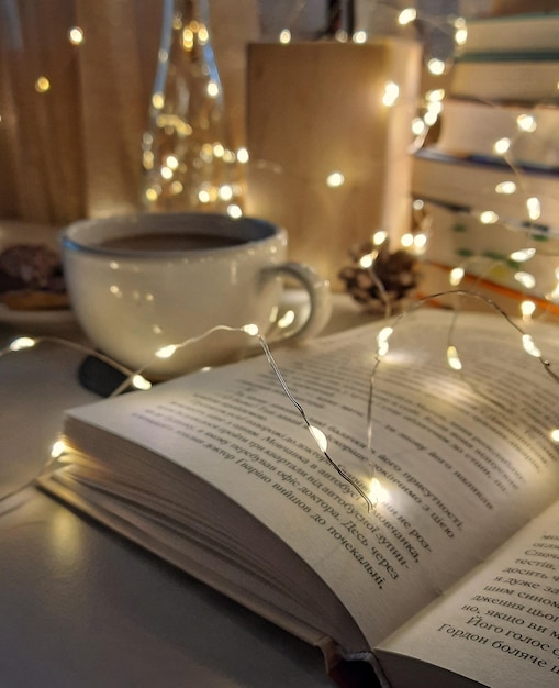 Vista ravvicinata dei libri del libro aperto nella ghirlanda posteriore e nella tazza di caffè