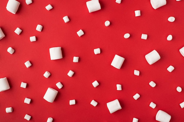 Close up view photo picture of tasty small and large different size marshmallow lying on vivid color red background