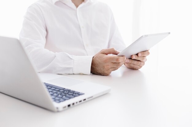 Close-up view of professional businessman using tablet against white desk