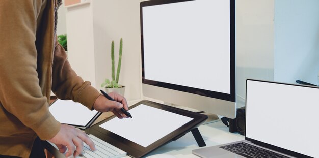 Vista del primo piano del grafico maschio professionale che lavora al suo pro getto con la compressa digitale dello schermo in bianco