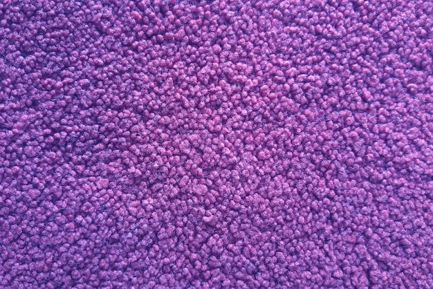 Close up view of purple carpet texture. Fabric textile floor rug surface.