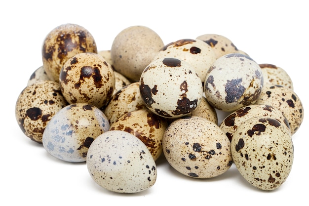 Chiuda sulla vista delle uova di quaglia crude isolate su una priorità bassa bianca.