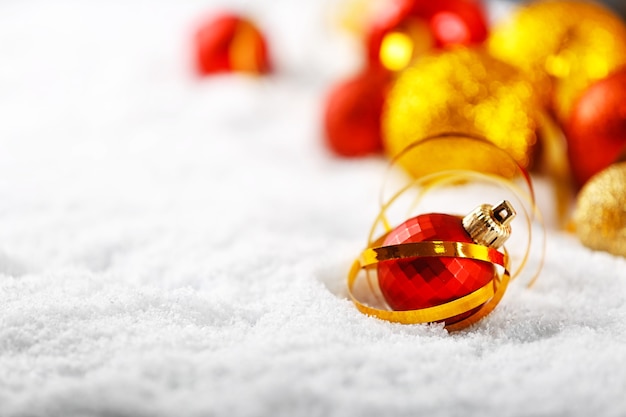 Close up view of red Christmas bauble and ribbon on white snow