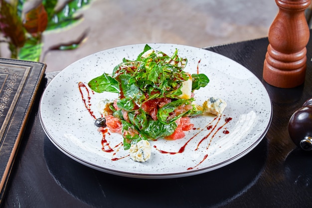 Close up view on salad with spinach, blue cheese and grapefruit on dark background. Modern cuisine. Healthy food for lunch. diet and balance food. Front view. Copy space