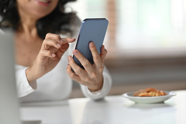 携帯電話でマッサージを入力する年配の女性の接写 技術コミュニケーションのコンセプト