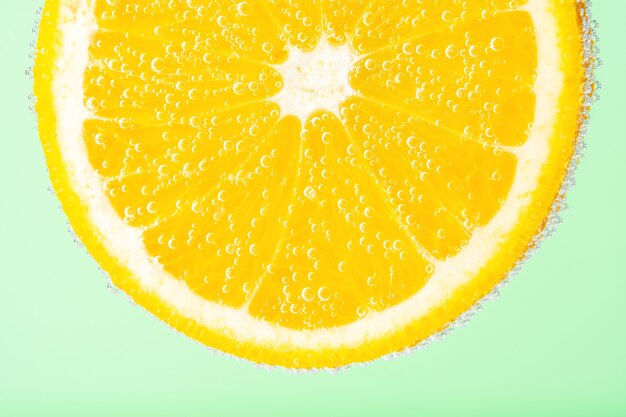 Vista ravvicinata di una fetta d'arancia in acqua di soda con bolle