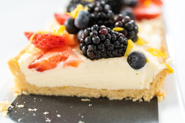 Close up view. Sliced mascarpone tart with fresh berries garnished with lemon zest.