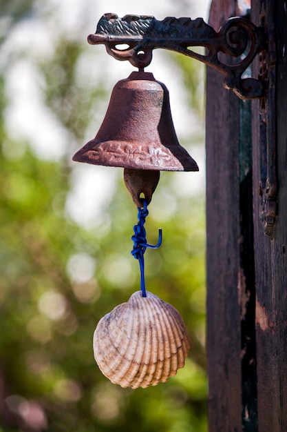 Close up view of a small rusty bell with a shell serving as a door bell.