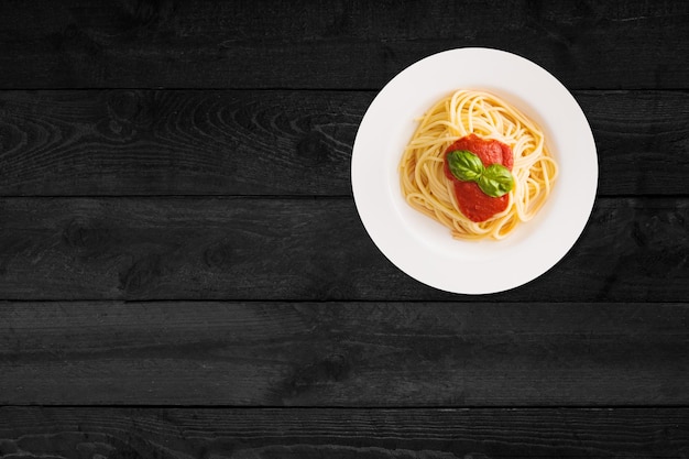 Close up view of spaghetti with ketchup isolated on black wooden table