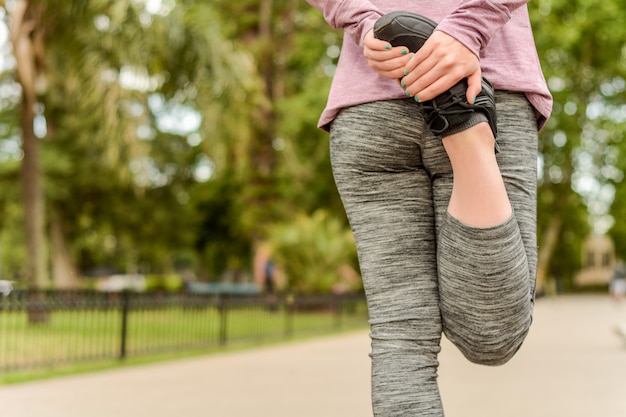 Foto chiuda sulla vista delle gambe streching della donna di sport