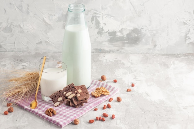 Vista ravvicinata di caramelle a forma di bastone in una bottiglia di vetro riempita con latte e biscotti punte di arachidi su asciugamano viola su sfondo grigio Foto Premium