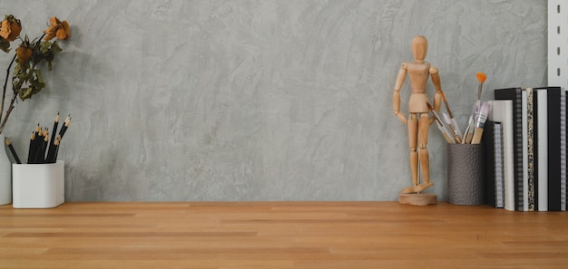 木製のテーブルと灰色の壁にオフィス用品とコピースペースを持つスタイリッシュなワークスペースのクローズアップビュー