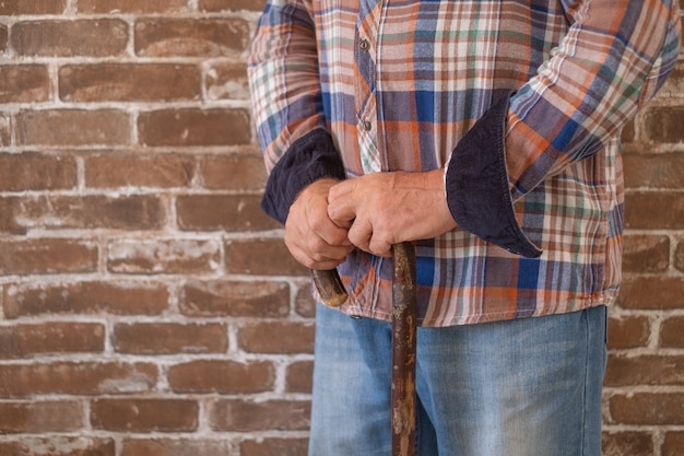 Close-up view of suffering elderly man walking with the help of a cane.