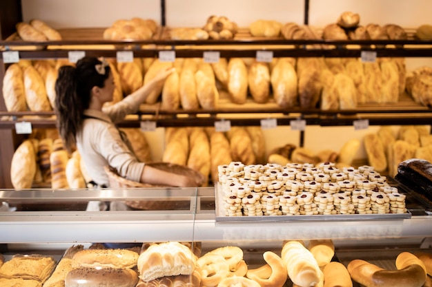 Close up view of tasty and delicious cookies in bakery shop and worker arranging pastry