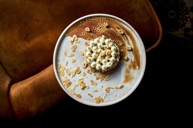 Close up view on tasty  Kyiv cake made of meringue with hazelnuts, chocolate glaze, and a buttercream-like filling. Cake on white plate