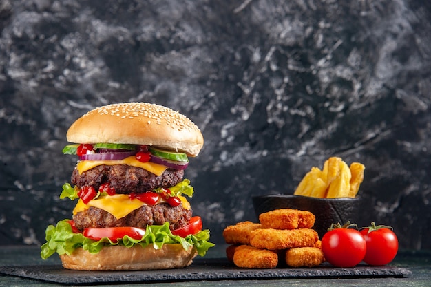 Close up view of tasty meat sandwich on dark color tray and chicken nuggets on black surface