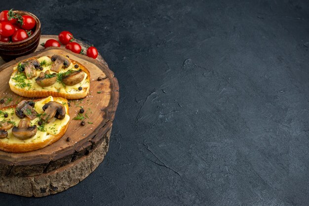 Close up view of tasty snack with mushrooms tomatoes salt on wooden board on the right side on black background