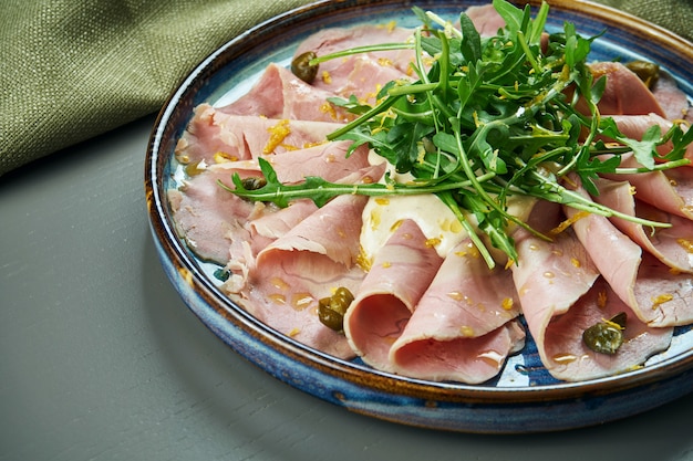 Close up view on traditional italian cuisine Vitello tonnato. A dish with pickled caper, veal, cream sauce on wooden table. Antipasti. Selective focus. Copy space