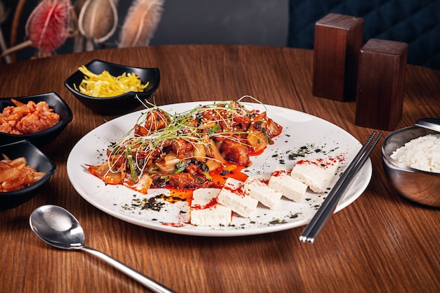 Close up view on traditional korean sliced pork in sweet and sour sauce with lettuce leaves. Meat served with kimchi. Korean cuisine with copy space. Food background.