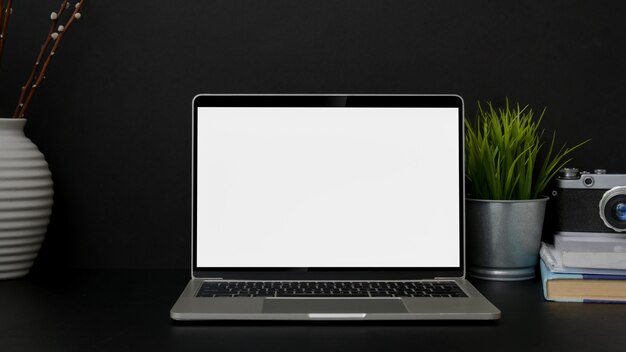 Close up view of trendy designer workplace with blank screen laptop on black table