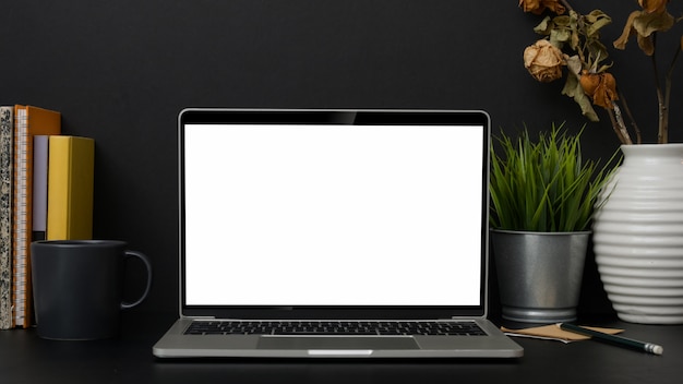 Close up view of trendy workplace with blank screen laptop, books and decorations