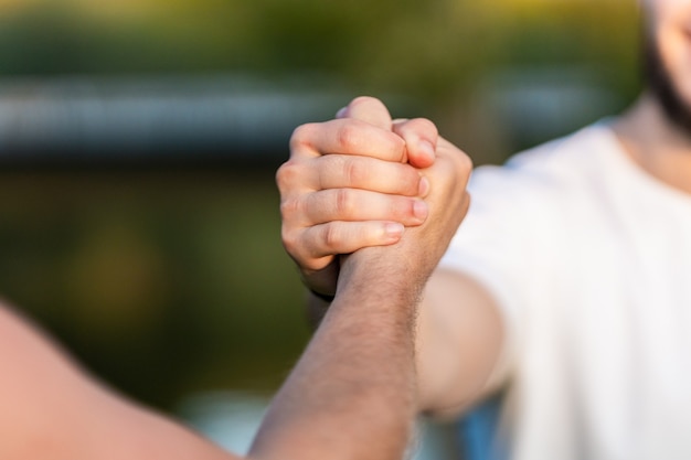 Close up view of two men shaking hands outdoors