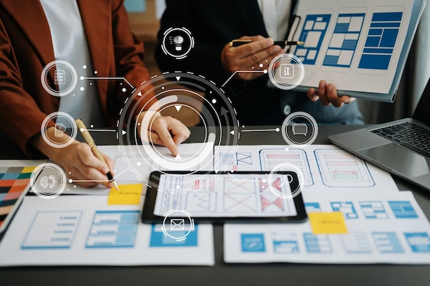 UI開発チームがラップトップスマートフォンデジタルタブレット仮想アイコンを備えたクリエイティブデジタル開発エージェンシーでプロジェクトについてブレインストーミングをしている