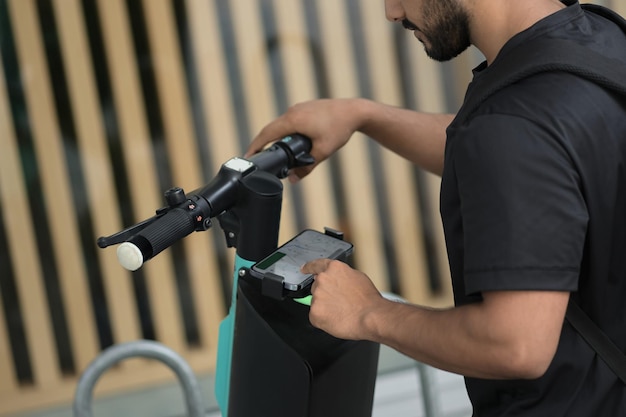 Close up view of the unknown man hands using mobile phone while unlocked scooter