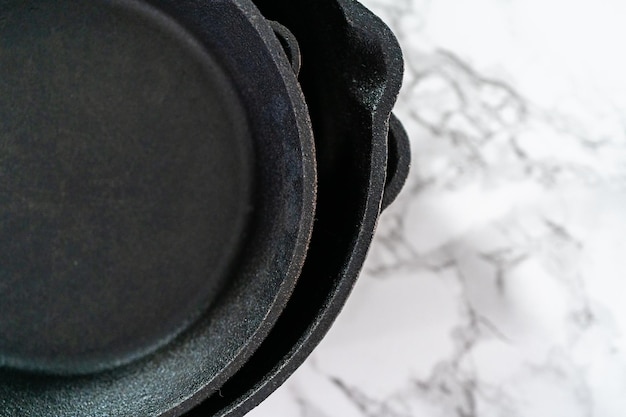 Close up view. Variety of cast iron frying pans on a marble background.