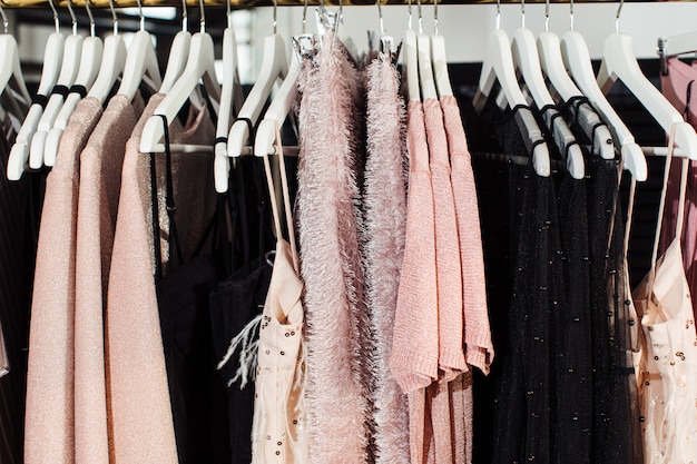 Close-up view of various stylish clothes hanging on hangers in boutique. Clothes